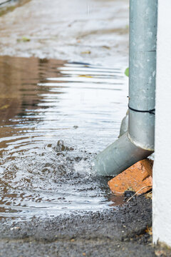 Water running out of a down pipe into a puddle