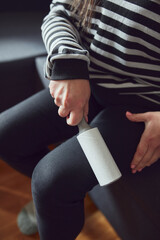 Woman cleaning clothes with a sticky lint roller.