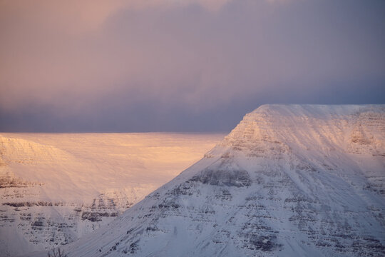 Snowy mountain peak catching first light of dawn in iceland