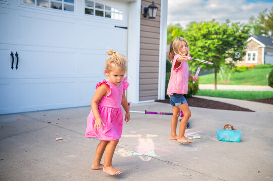 Young Sisters Playing Outside with Bubbles, Chalk, and Toys