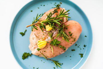 Raw chicken breast marinated with rosemary, garlic and herbs on a white background and vacuum bag.