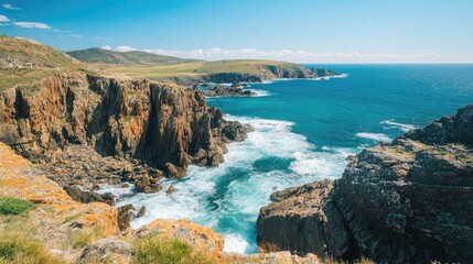 Obraz premium A panoramic view of a rugged coastline with waves crashing against the rocks and a clear blue sky.