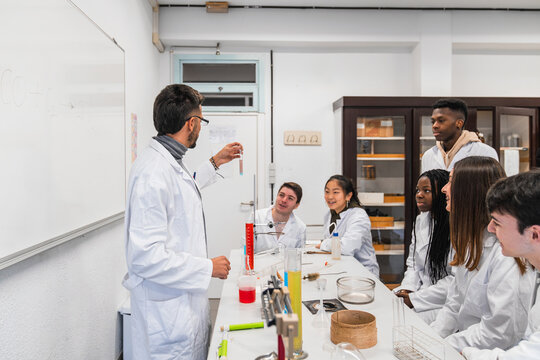 Chemistry teacher showing test tube to high school students in laboratory classroom - Powered by Adobe