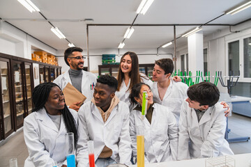 Happy students collaborating in chemistry lab experimenting with liquids