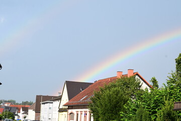 big rainbow in thunderstorm sky above a village