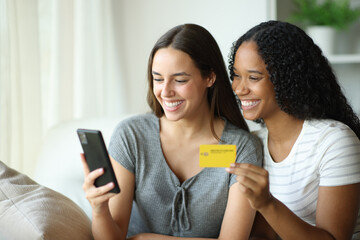 Happy interracial roommates buying online at home