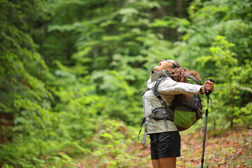 Excited trekker outstretching arms screaming in a forest