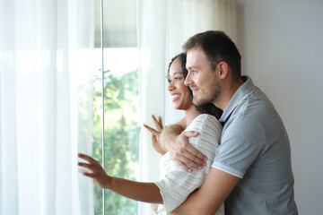 Interracial couple at home looking through the window