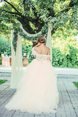 Fototapeta premium A bride in a soft pastel wedding gown sits on a decorated wooden chair labeled 