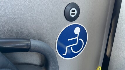 The international symbol of accessibility sign, indicating designated seating for passengers with disabilities on a bus of public transportation provided for passengers with diverse needs.