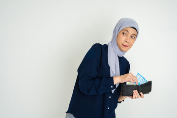 A young woman wearing a headscarf opens a wallet filled with various cards, glancing aside with a notable expression that implies curiosity, caution, or thoughtfulness.