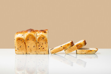 Freshly baked whole grain bread with slices on beige and white background.