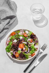 Vegetable salad (Greek salad) with cherry tomatoes, feta cheese, lettuce, olives and red onion in a plate