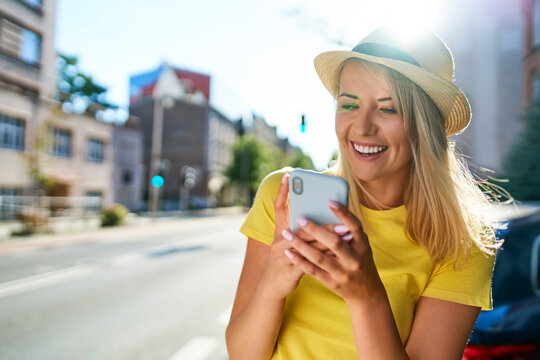 Happy young woman using smartphone in the city