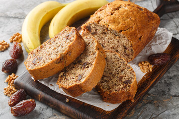 Gluten free and lactose free Date banana walnuts bread loaf close up on wooden board on table. Horizontal