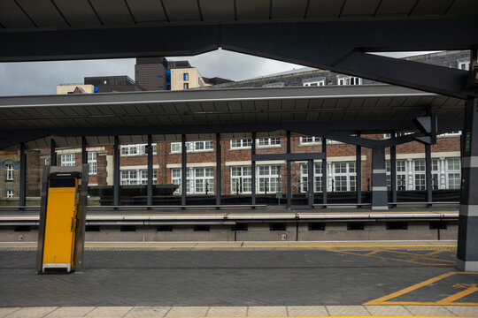Empty railway platform under a modern canopy structure. Geometric patterns create a striking perspective in this urban transit hub.