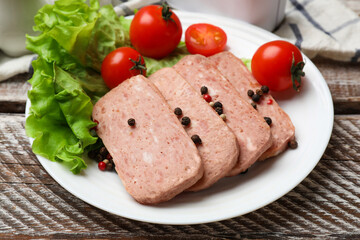 Tasty canned meat, tomatoes, lettuce and spices on wooden table, closeup