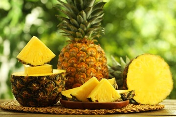 Fresh ripe pineapples on wooden table against blurred background