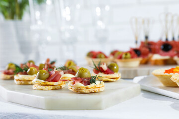 Many different tasty canapes on white wooden table, closeup