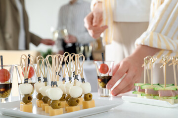 Many different tasty canapes on white table. People enjoying buffet meals indoors, closeup