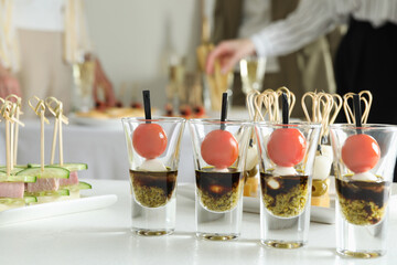 Many different tasty canapes on white table. People enjoying buffet meals indoors, closeup