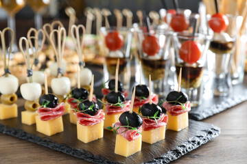 Many different tasty canapes on wooden table, closeup