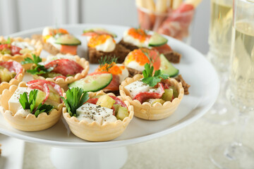 Many different tasty canapes and wine on white table, closeup