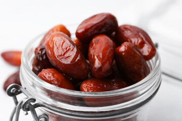 Tasty dried dates in jar on white table, closeup