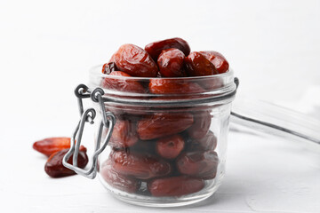 Tasty dried dates in jar on white table, closeup