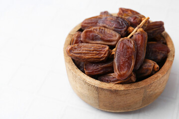 Tasty dried dates on white tiled table, closeup. Space for text