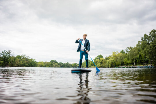 Businessman stand up paddling on a lake