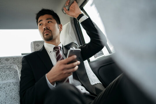 Young businessman with cell phone in a taxi