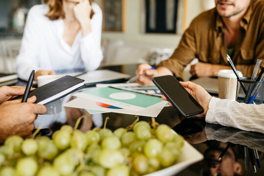 Close-up of coworkers working together on table