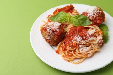 Delicious pasta with meatballs, cheese and basil on green table, closeup