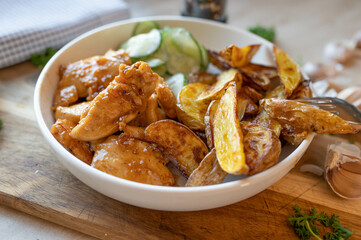 Chopped and pan fried chicken breast in a delicious honiy, butter, garlic sauce with potato wedges and cucumber salad