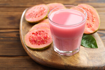 Tasty guava juice in glass, leaf and slices of fruits on wooden table, closeup