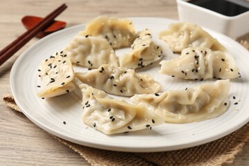 Delicious gyoza dumplings with sesame seeds served on wooden table, closeup