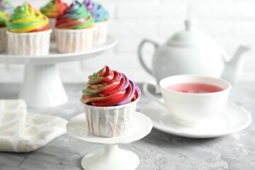 Delicious cupcake with colorful cream on grey textured table, closeup