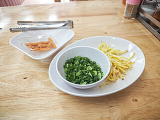 Fresh chopped chives, ginger, and snacks on a wooden table, ready to eat