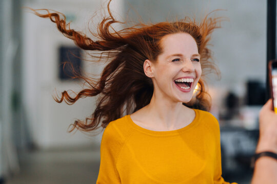 Laughing woman with windswept hair in office
