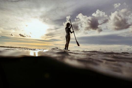 Female SUP surfer at sunset, Bali, Indonesia
