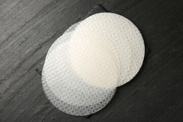 Edible rice paper sheets on dark textured table, top view