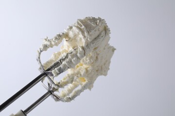 Whisks with whipped cream on white background, closeup. Space for text