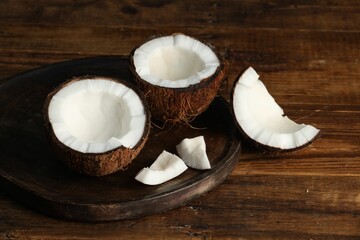Pieces of cracked coconuts on wooden table, closeup