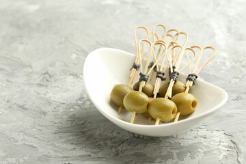 Tasty marinated olives on grey textured table, closeup. Space for text