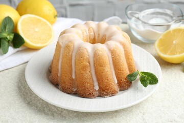 Delicious lemon cake with glaze, mint and citrus fruits on light textured table, closeup