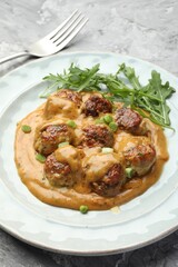 Delicious meatballs with gravy cream sauce, herbs and arugula served on grey table, closeup