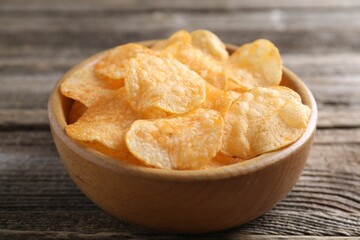 Tasty potato chips in bowl on wooden table, closeup