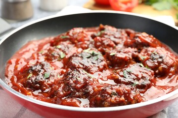 Delicious meatballs with tomato sauce and herbs in on table, closeup
