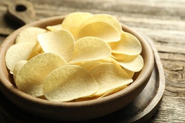 Tasty potato chips on wooden table, closeup